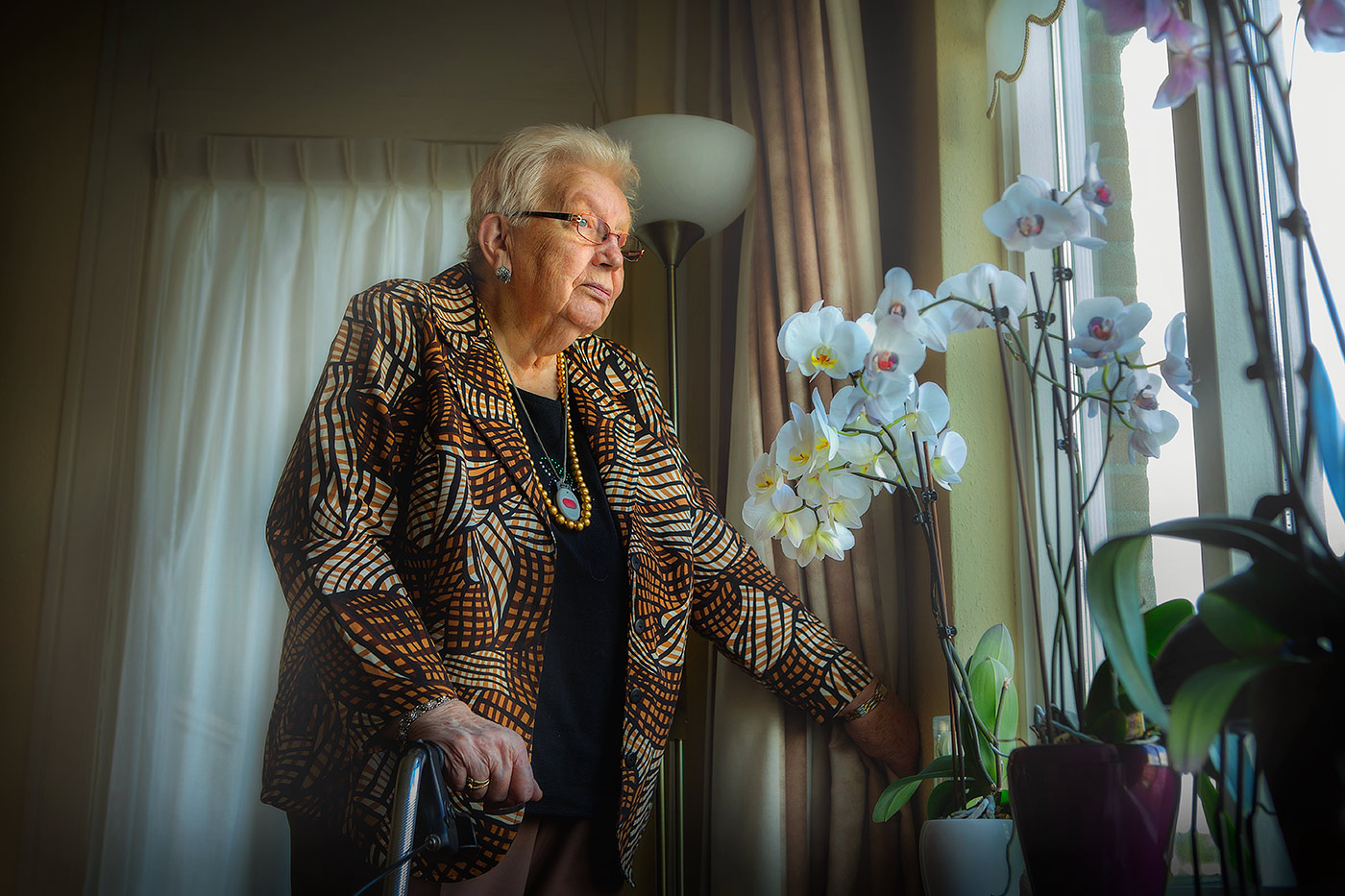 bejaarde vrouw kijkt uit het raam ouderenzorg en eenzaamheid